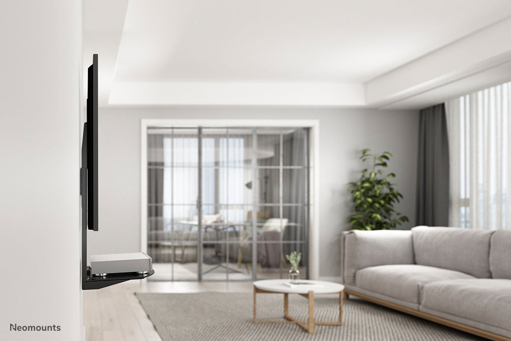 Neomounts AV-fäste, modell NS-SHELF100 är idealiskt för att placera AV-utrustning under väggfästen för platt-TV.